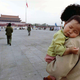 A child sleeps on his mother’s shoulder as she crosses Tiananmen Square.